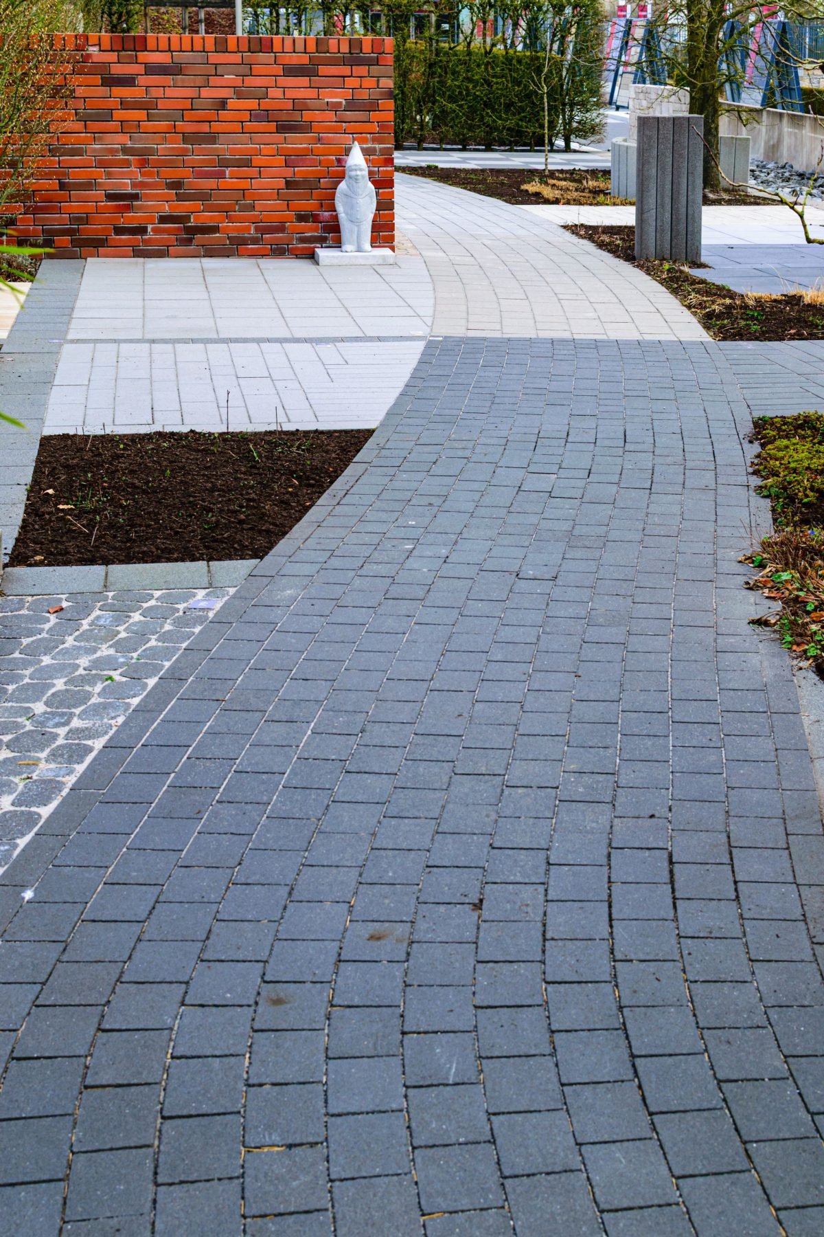Curved interlocking brick pathway laid through a landscaped garden